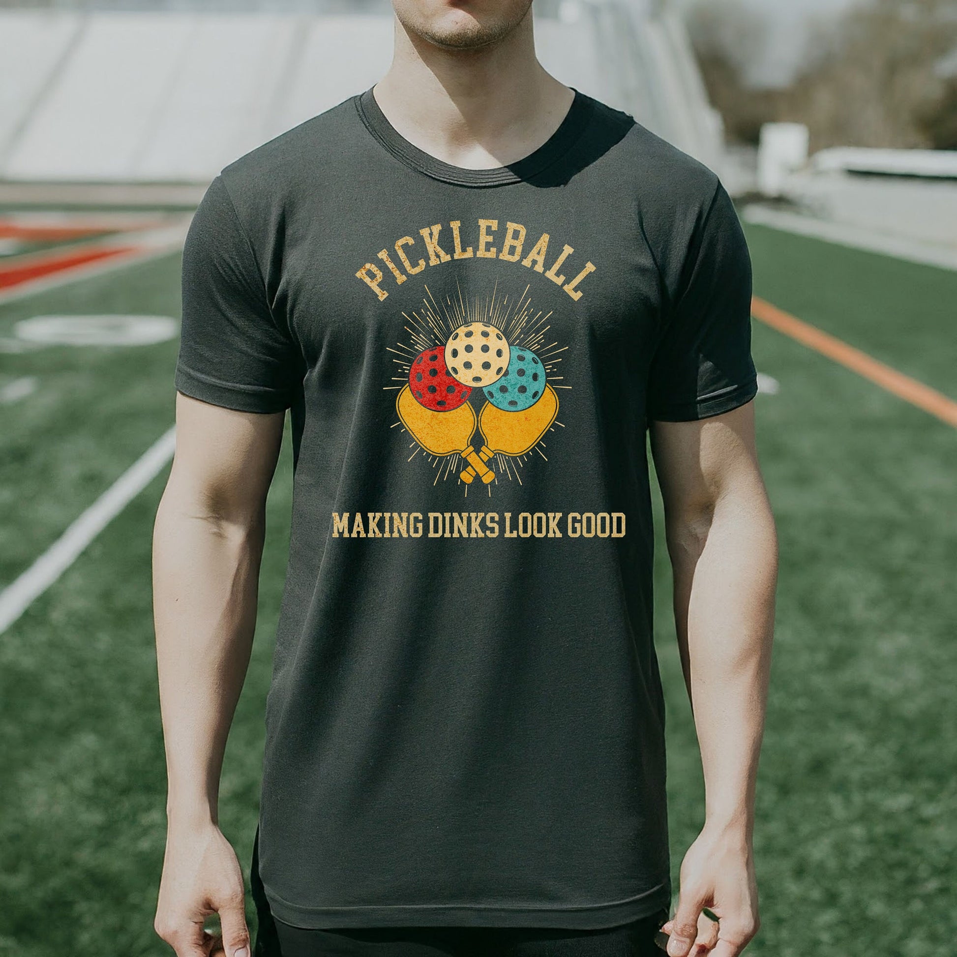 a man wearing a pickleball shirt standing on a field