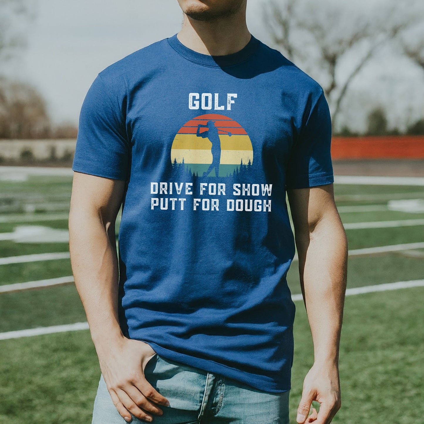 a man standing on a field wearing a blue golf t - shirt