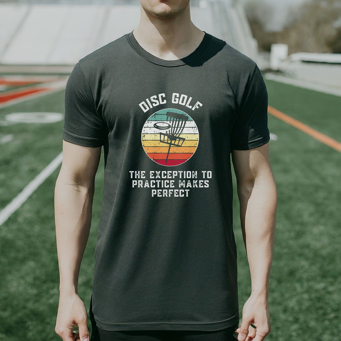 a man standing on a field wearing a disc golf shirt