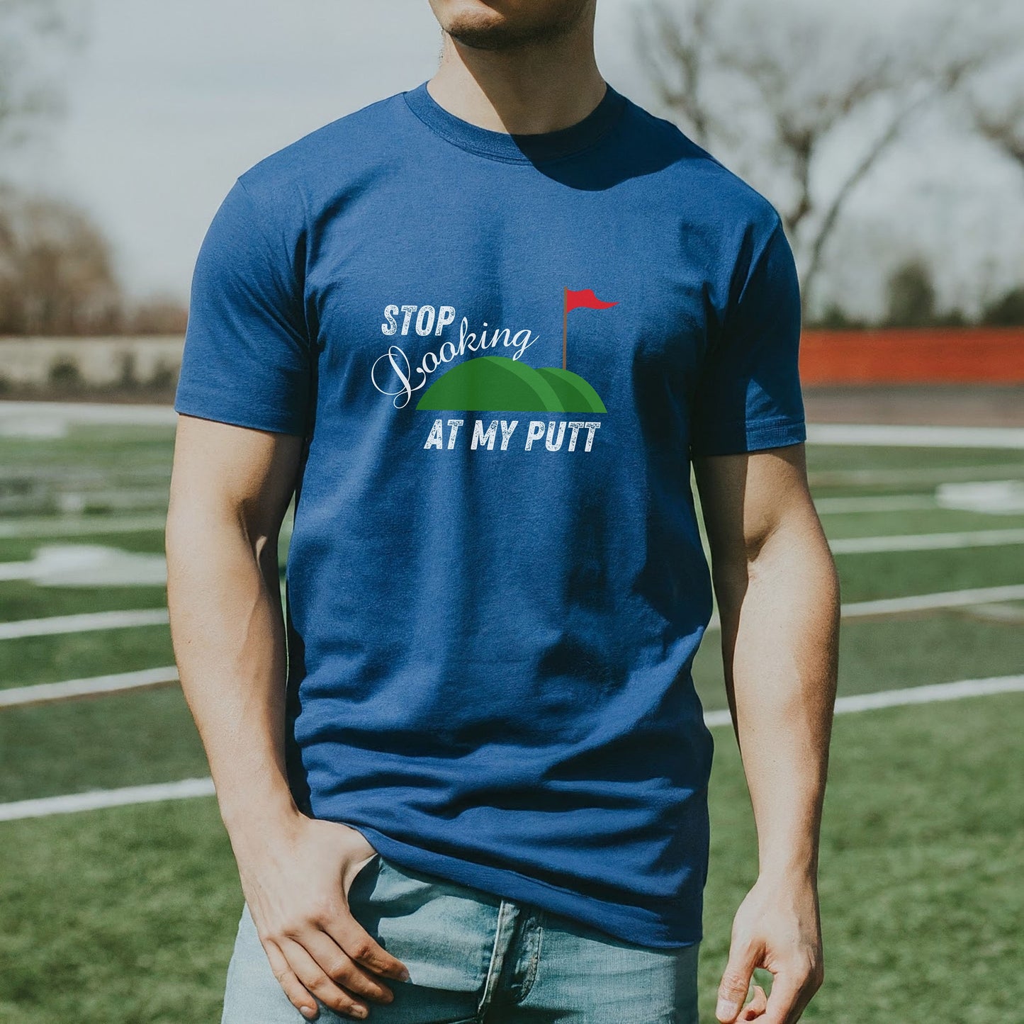 a man standing in a field wearing a blue t - shirt