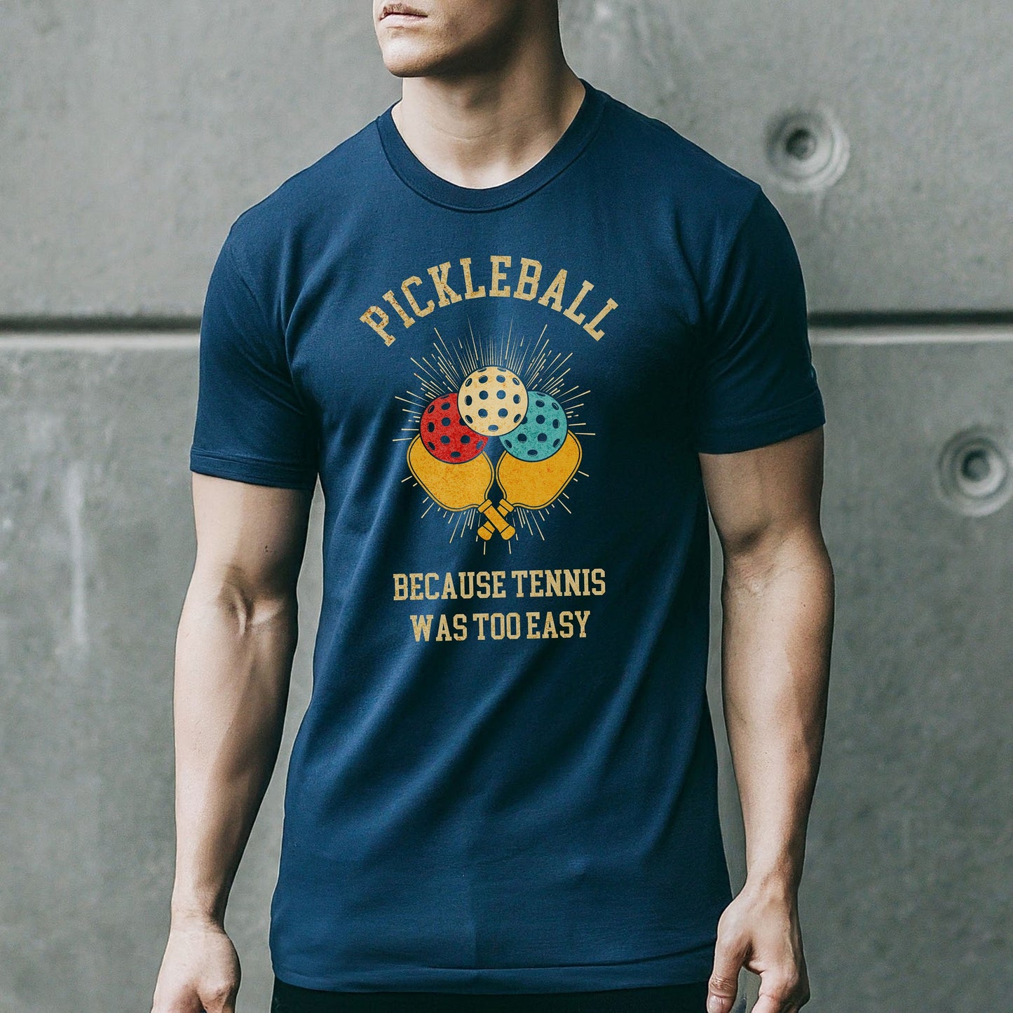 a man wearing a pickleball t - shirt while holding a tennis racket