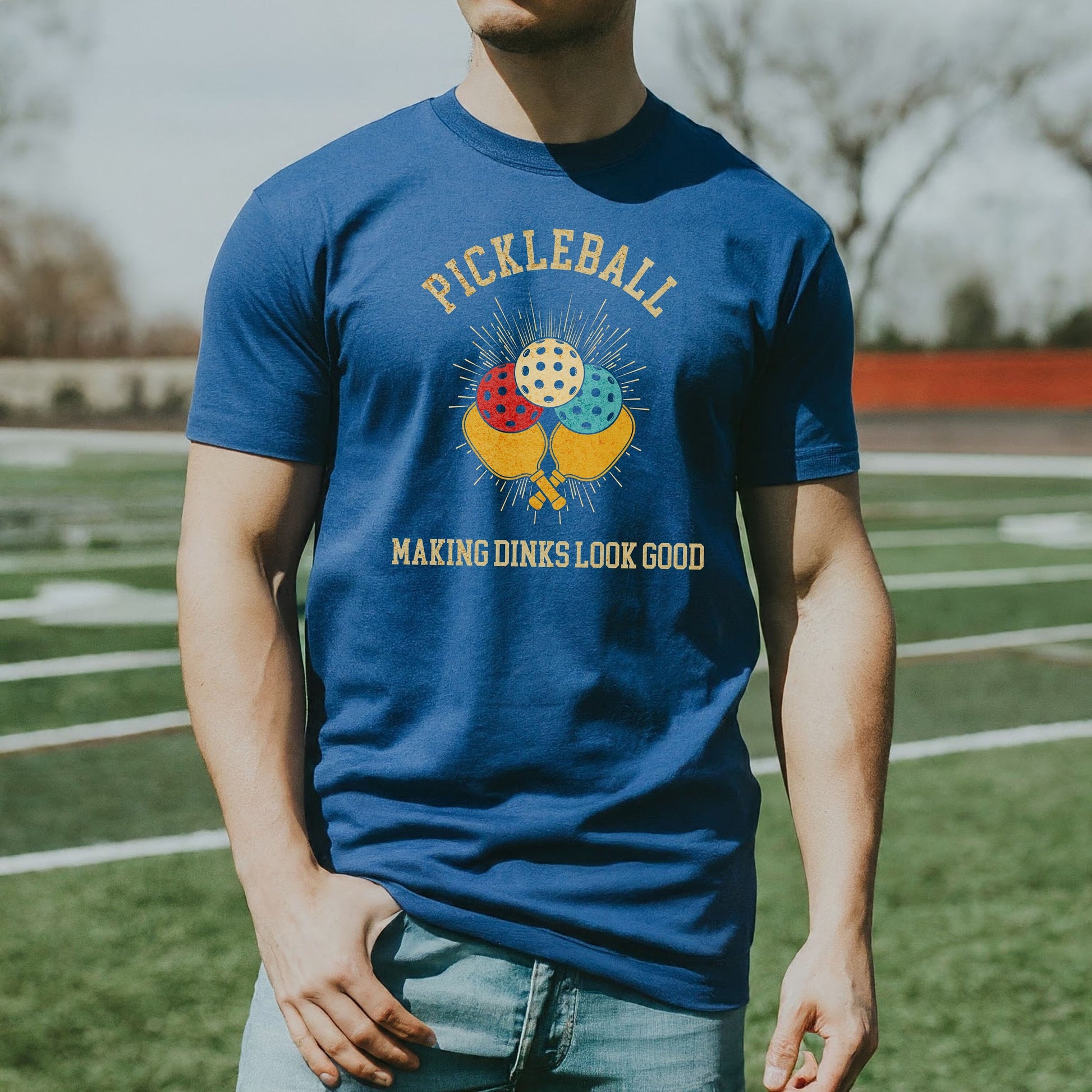 a man wearing a pickleball t - shirt standing on a field