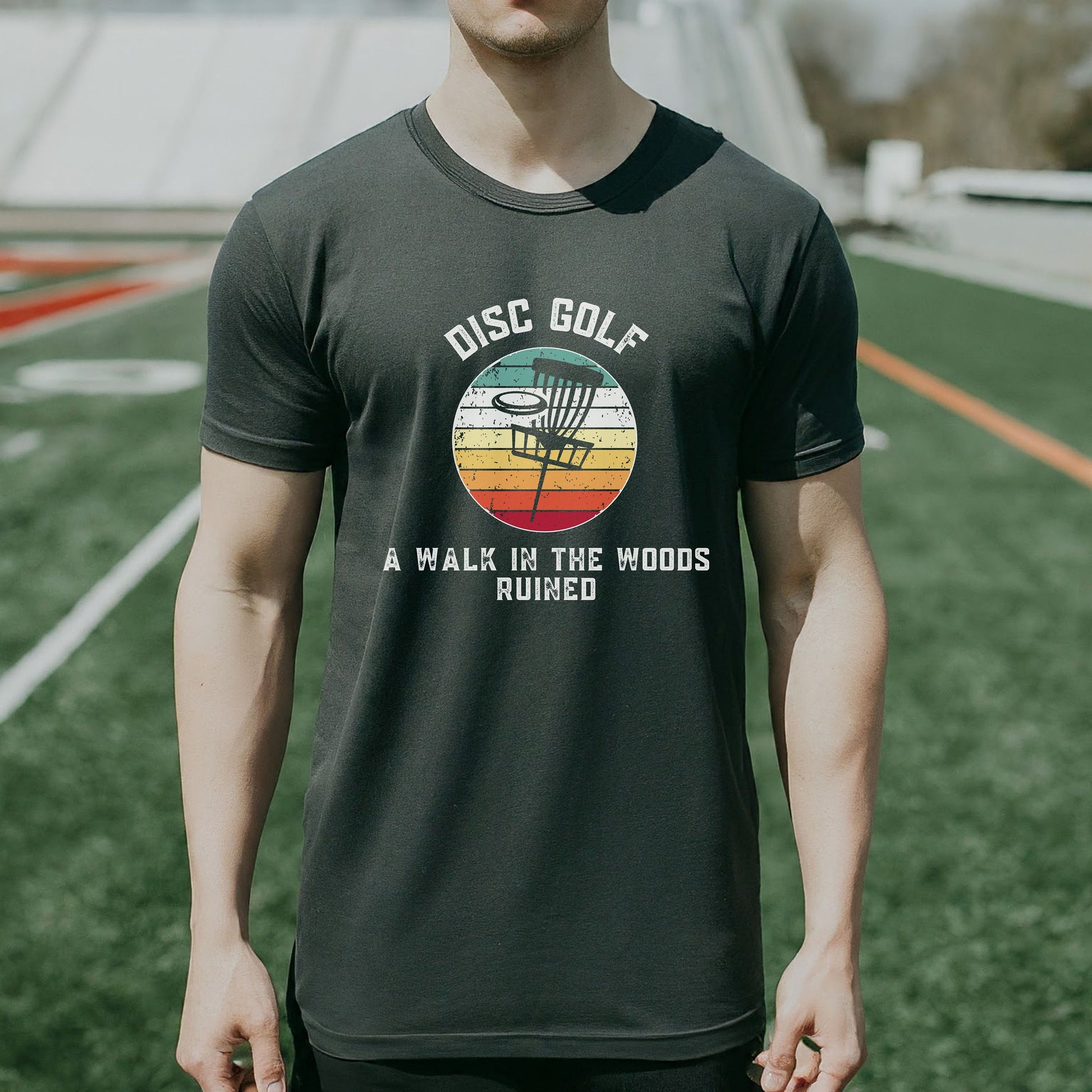 a man standing on a field wearing a disc golf shirt