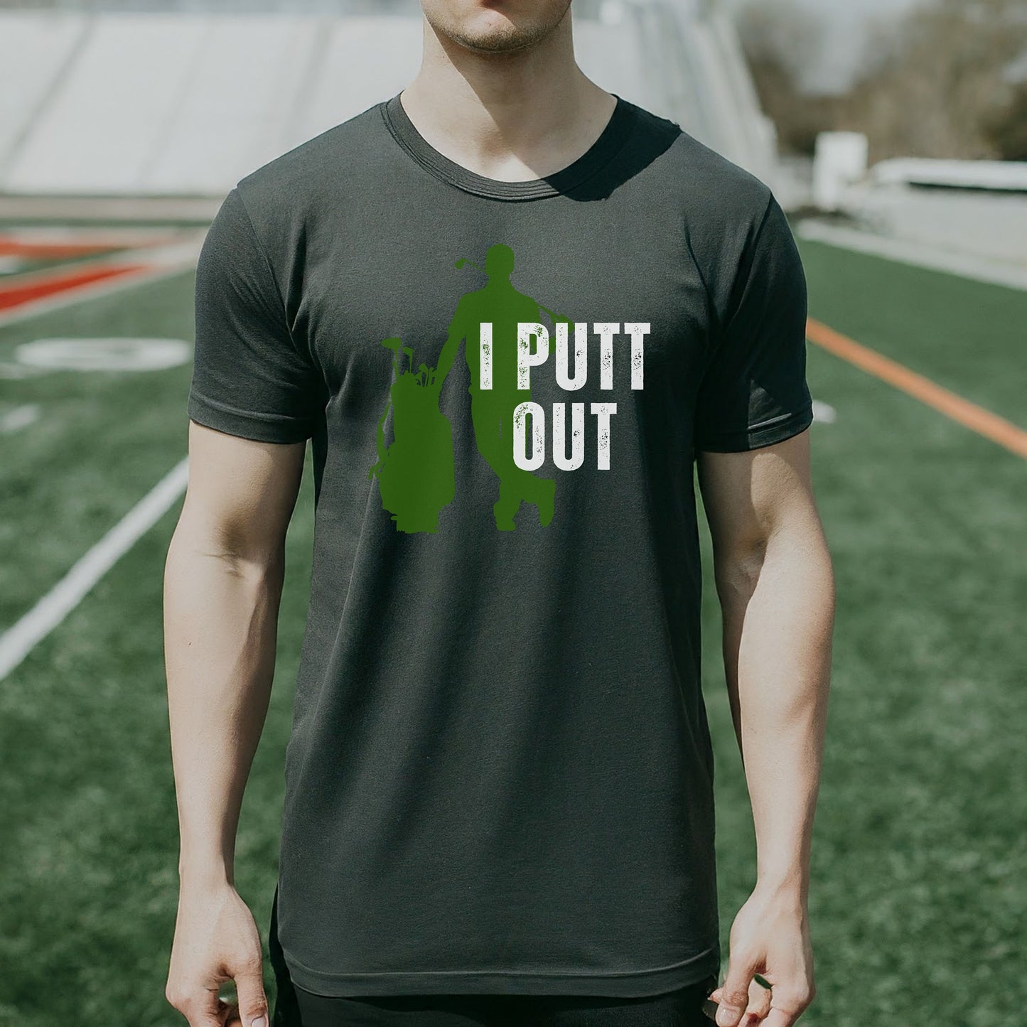 a man standing on a field wearing a shirt that says i putt out